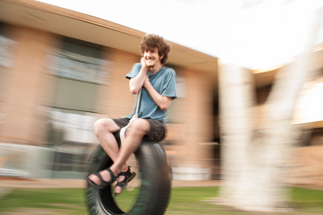 Panned photograph of student swinging on campus at HMC. Harvey Mudd College